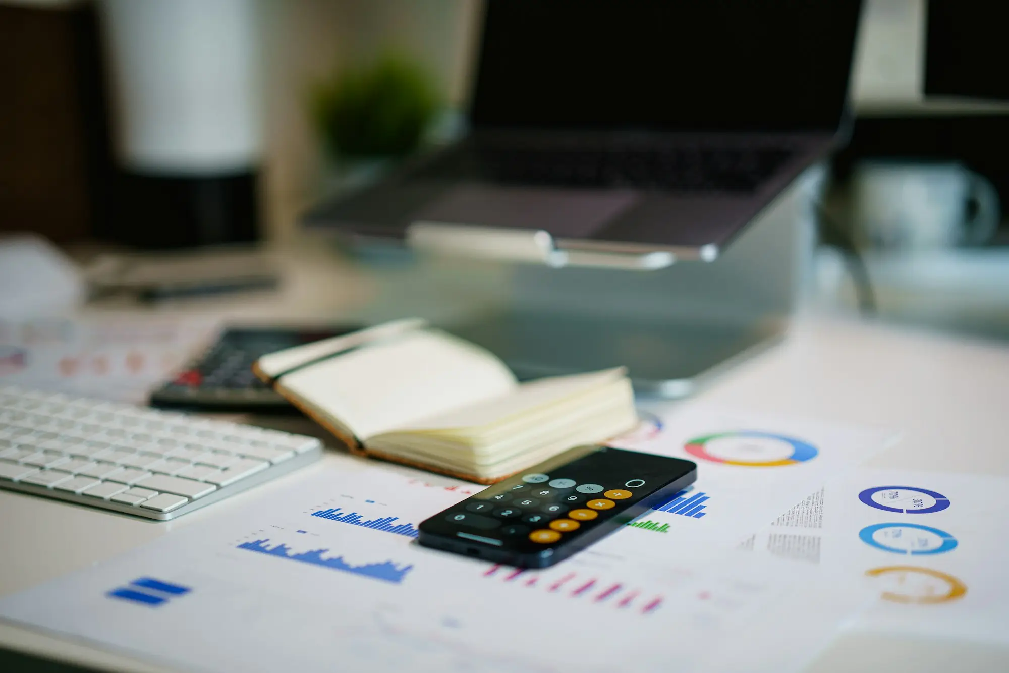Calculator, notebook and invoices spread across an office desk