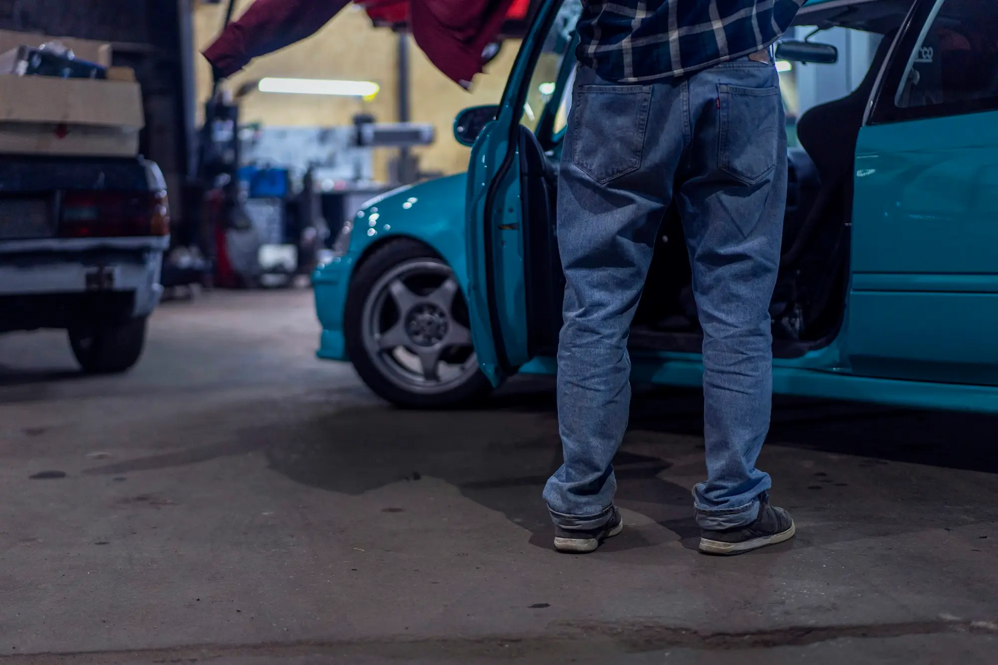 Workshop owner standing beside a customer's car in the service bay